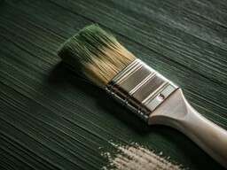 Paint Brush and Some White Paint on a Green Table