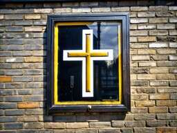 Yellow Cross on the Side of a Building
