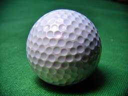 White Golf Ball Sitting on Top of a Green Table