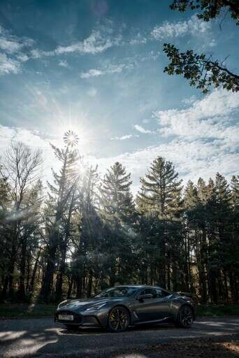 A Silver Sports Car Parked In Front Of A Forest