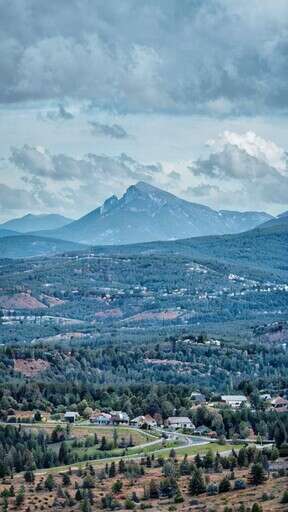A View Of A Mountain Range With A Small Town In The Foreground