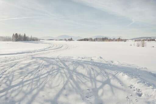 A Snow Covered Field With Tracks In The Snow