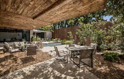 a patio with a table chairs and a pool in the background
