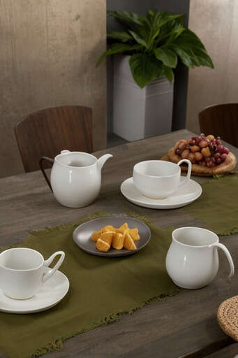 A Table Set With A Tea Pot, Cups, Plates, And Fruit On It