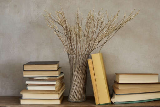A Vase Filled With Books And A Bunch Of Branches On A Table