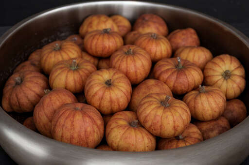 A Lot Of Small Pumpkins In A Bowl On The Table